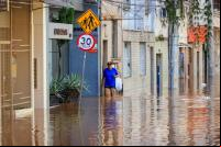 pessoa caminha em meio a enchente em porto alegre