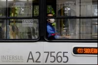 homem dentro de ônibus público com janela aberta e máscara