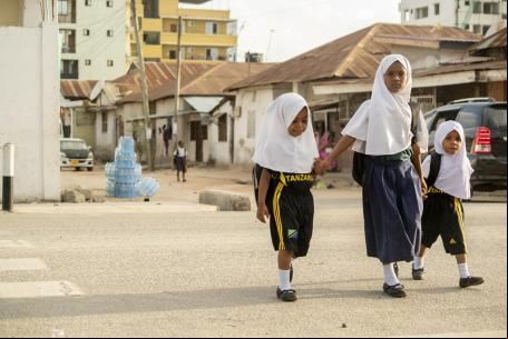 Três estudantes atravessam a rua em Dar es Salaam, na Tanzânia.